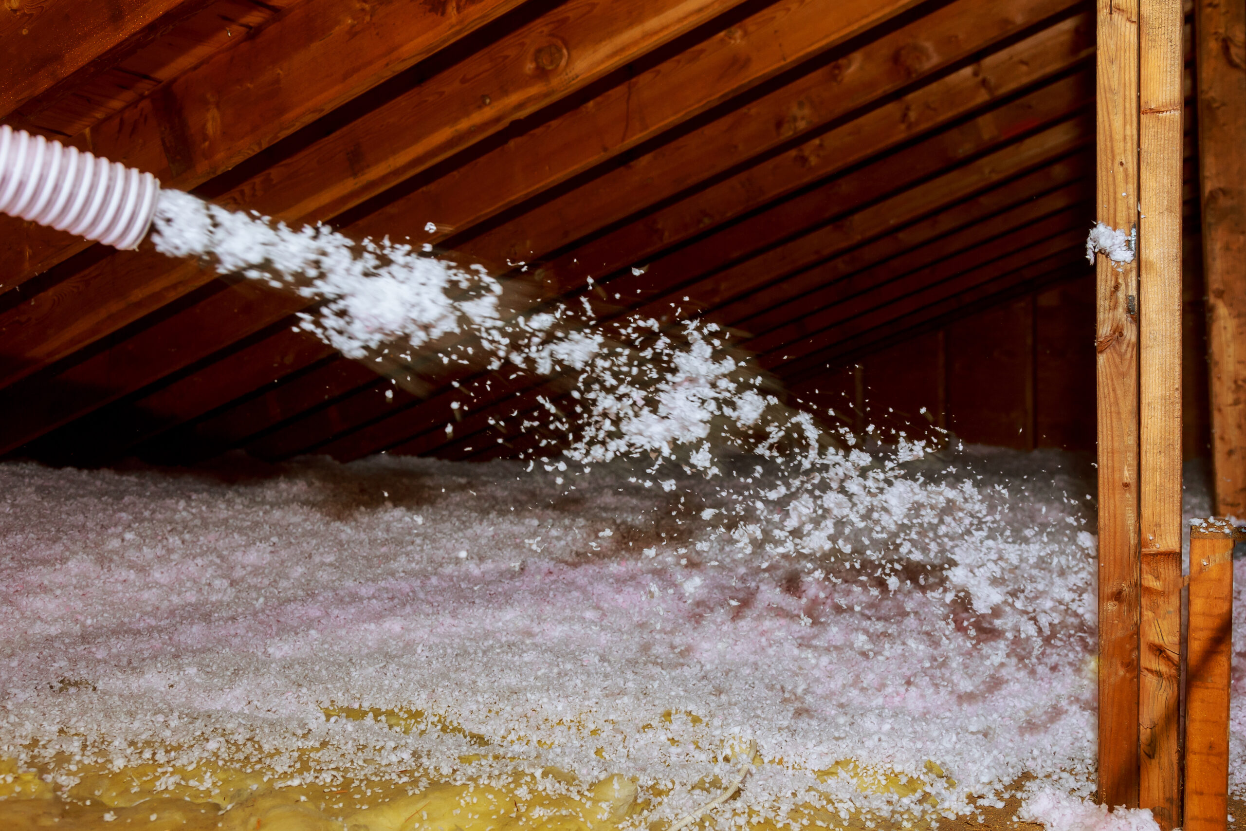 Services worker spraying mineral rock wool of house attic insulation